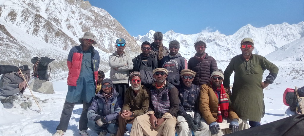 Dedicated group of mountain porters and field staff resting on high snow pass